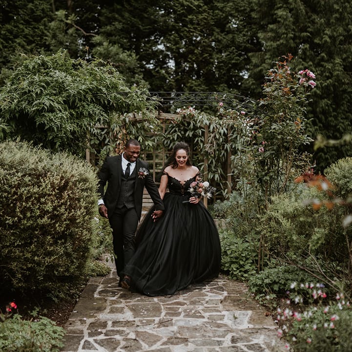 Bride & groom walk through gardens on their wedding day