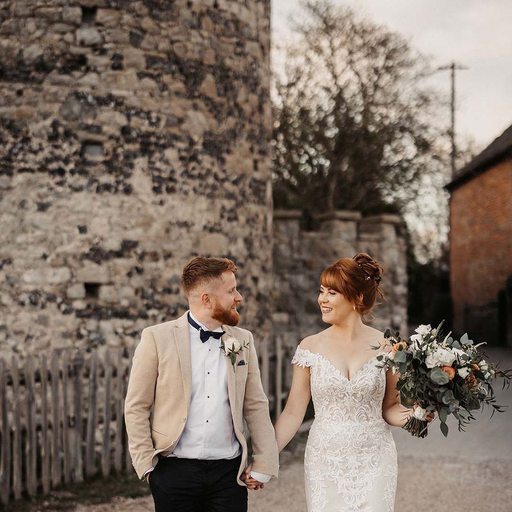Bride in Maggie Sottero off the shoulder lace wedding dress with groom in beige suit jacket for rustic barn spring wedding