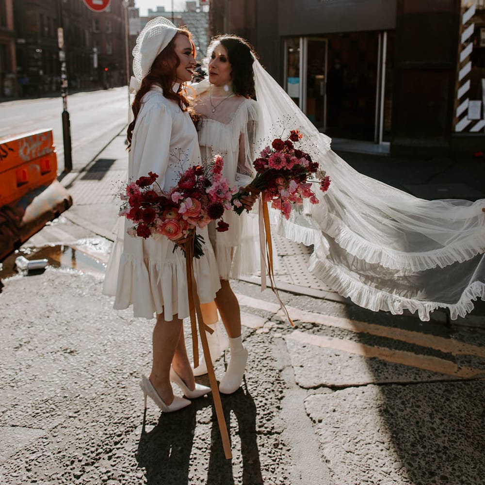 Two bride in boots, short wedding dress long veil wedding outfit and berret hat, high neck wedding dress with long sleeves. 
