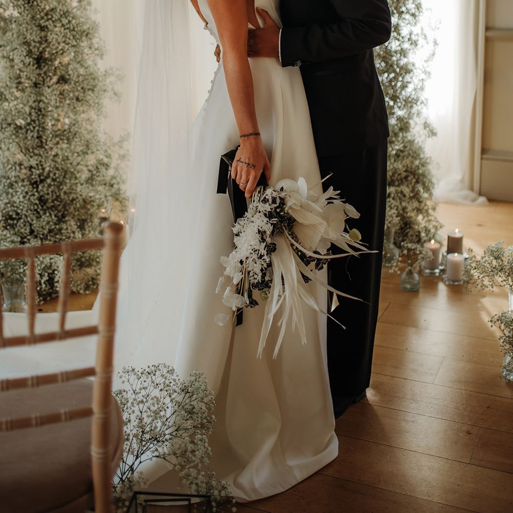 LGBTQI+ couple kissing at their Hodsock Priory wedding ceremony with drapes and gypsophila column flowers 
