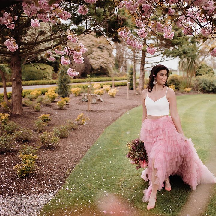 Bride in a pink ruffled wedding skirt and white crop top in the gardens at Ballykealey House wedding venue in Co. Carlow, Ireland
