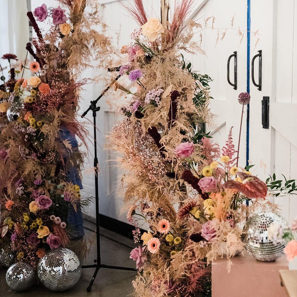 Colourful flower columns with dried grass and large disco balls for altar decoration