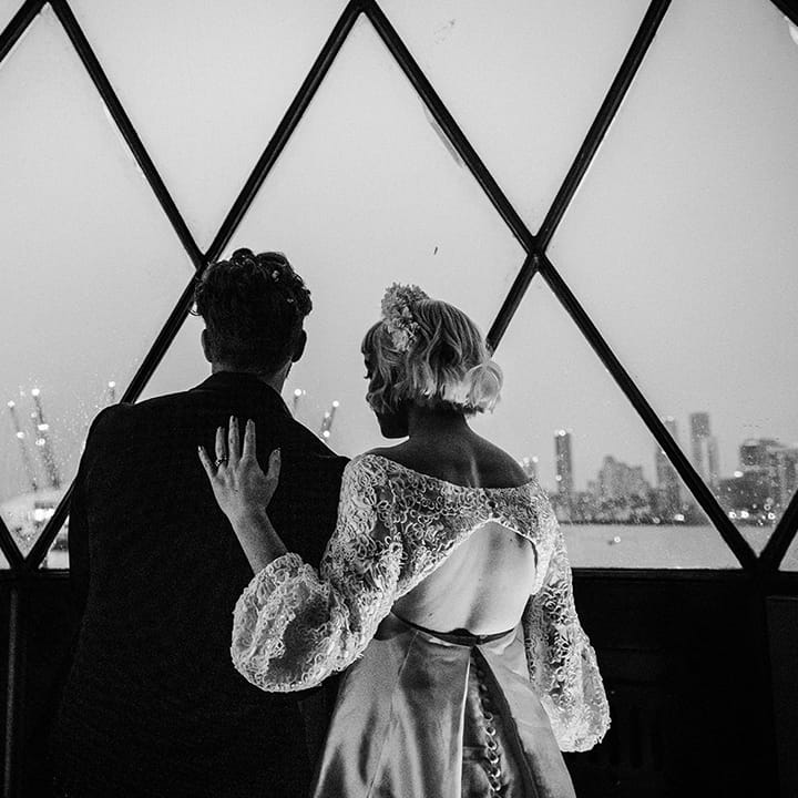 Bride and groom overlook the skyline of London with view of the Millennium Dome