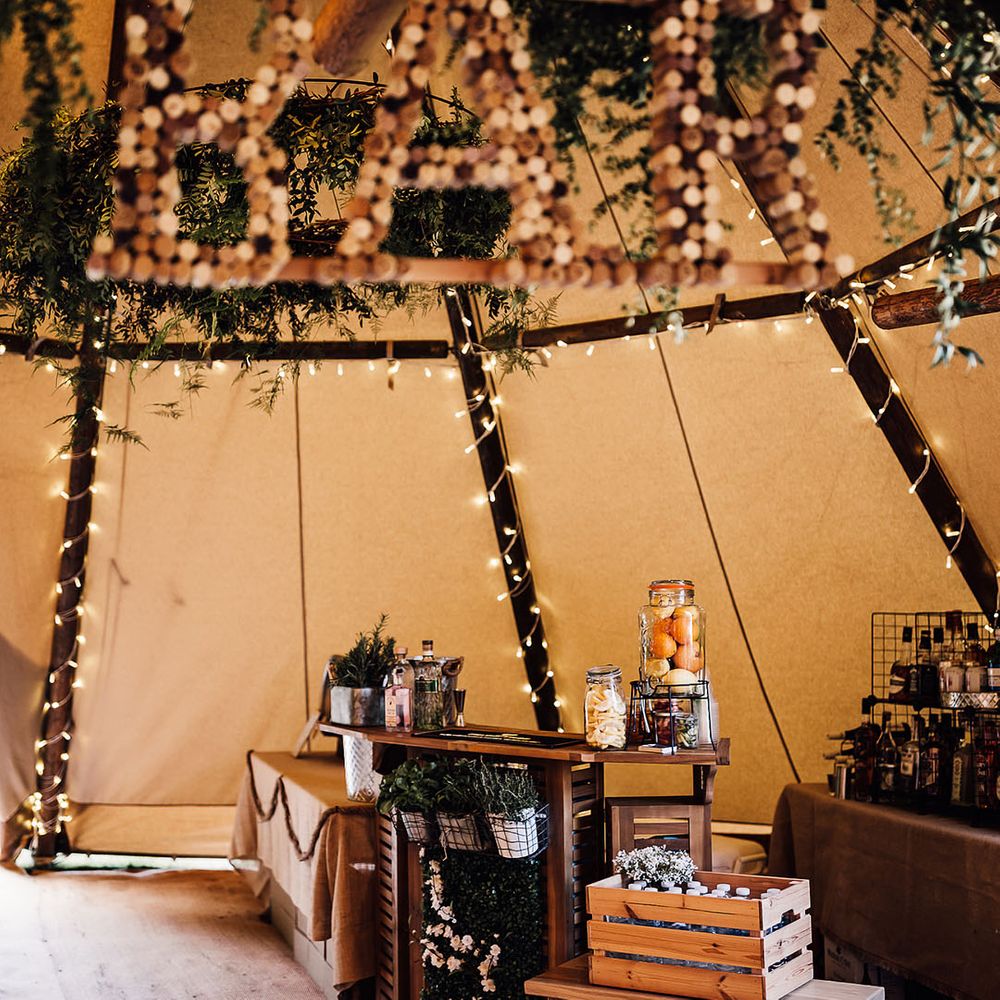 Bar area with bottles of water, juices, fruits and alcohol in tent for wedding reception 