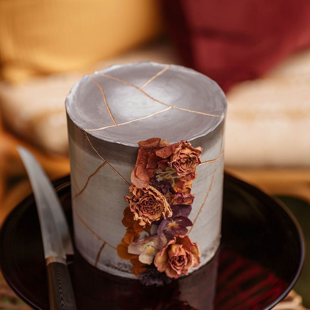 Single tier grey marble effect wedding cake with orange cascading wedding flowers on a black cake stand for Japanese wedding
