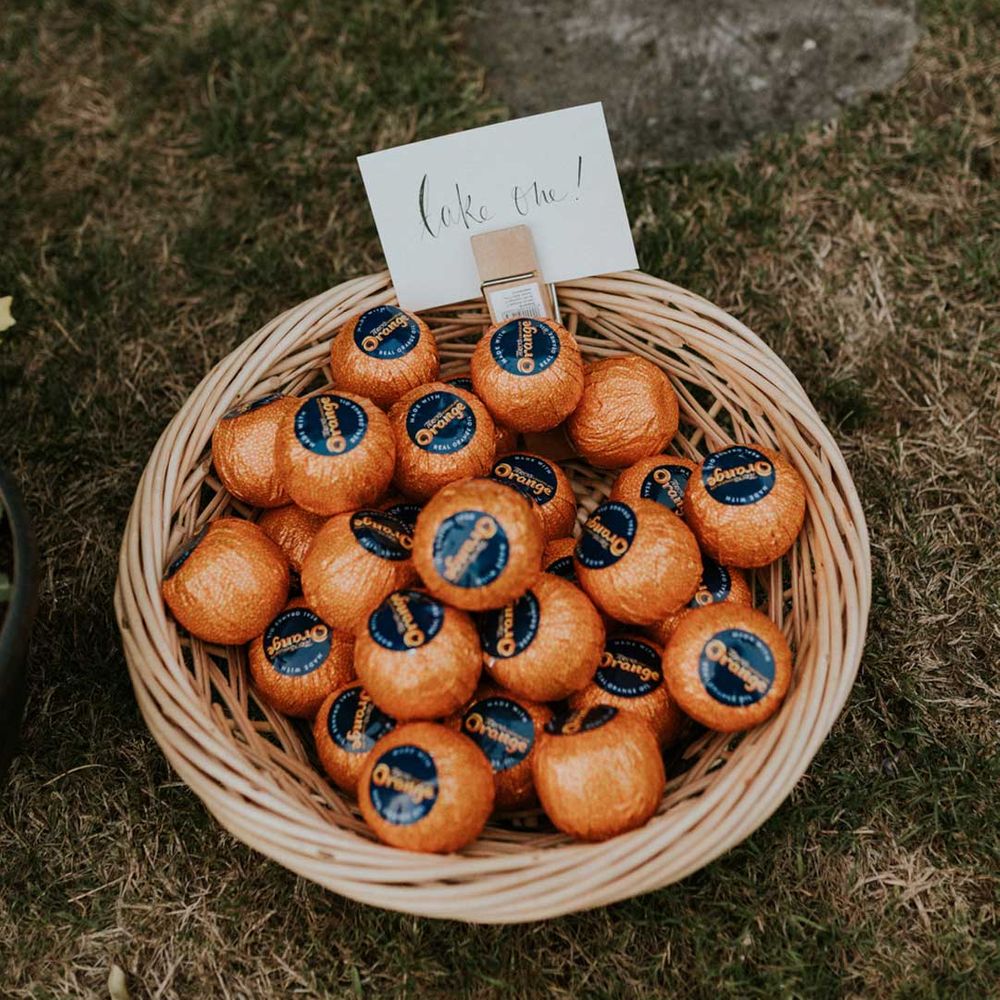 DIY wedding treats - chocolate oranges in a wicker basket with DIY sign saying take me attached
