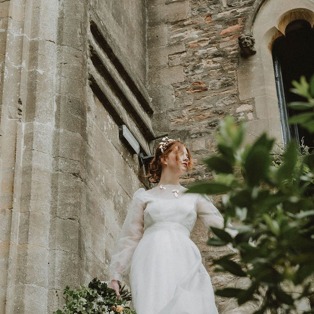 Bride in a sustainable fabric wedding dress with two layers and gold leaf jewellery at Bishop's Palace Wells