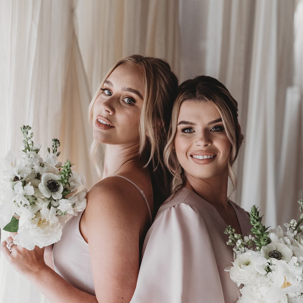 Bridesmaids with bouquets of white flowers in pale pink dresses 