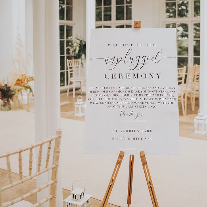 White wedding signage for unplugged wedding ceremony on wooden easel 
