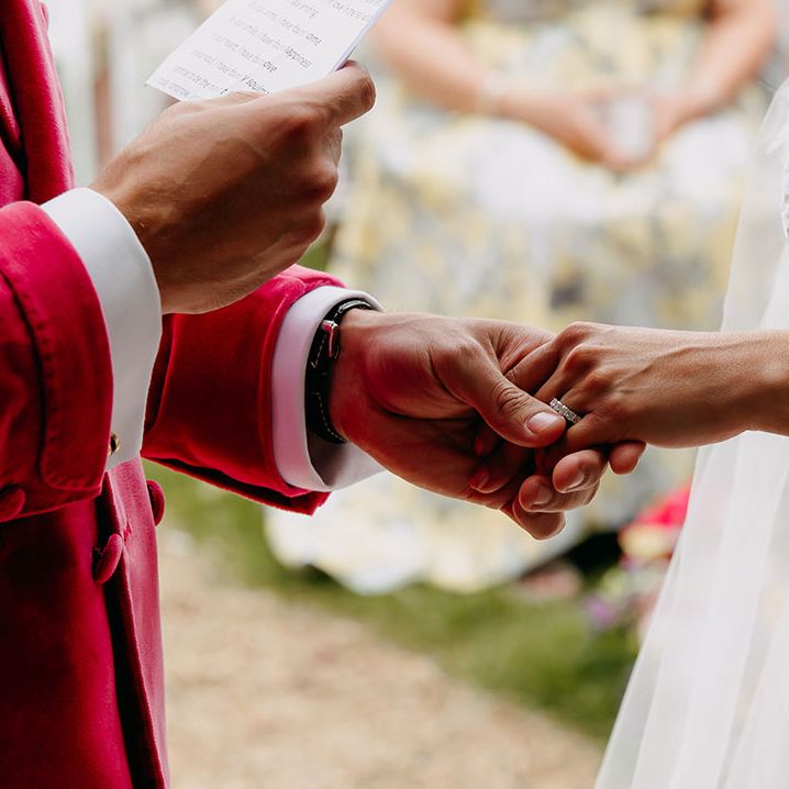 Groom reads out his wedding vows as he holds the bride's hand with her round diamond wedding band 