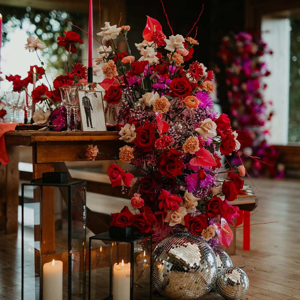 Pillar candles in large glass black metal lanterns, large disco ball wedding decorations, and tablescape flower arrangements with hot pink, bright pink and viva magenta dahlias, orchids, roses, amaryllis, anthuriums and dried flowers 