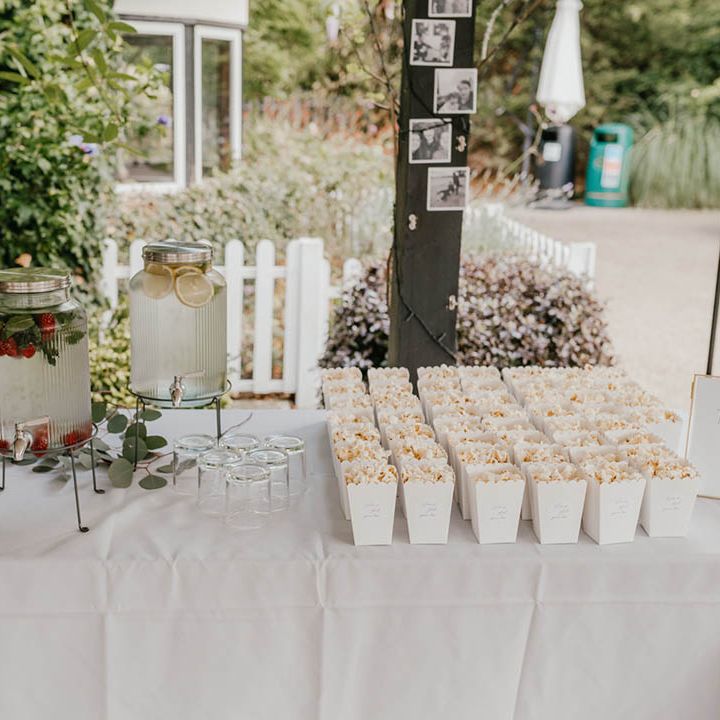 Fruit infused water next to boxes of popcorn for fun ways to serve food and drinks to the wedding guests 