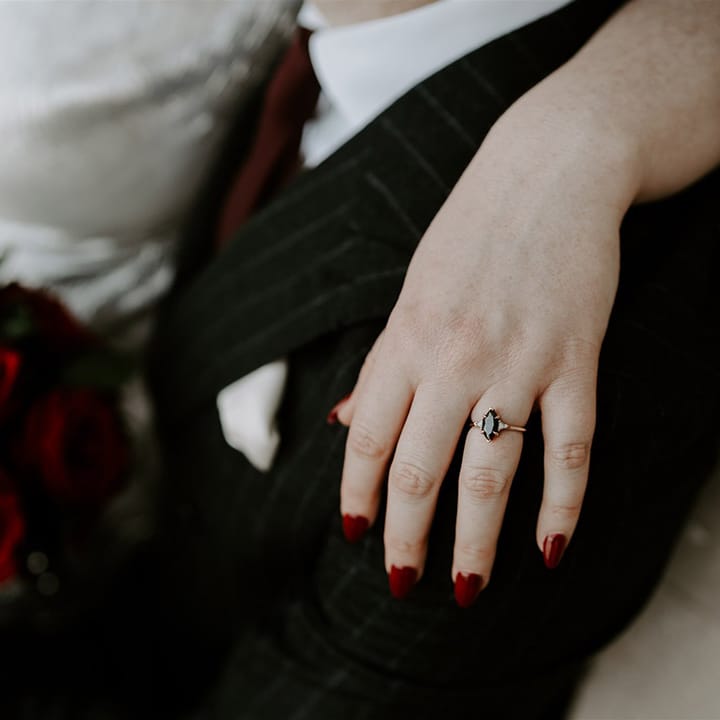 Black marquise wedding ring with gold wedding band worn by bride with red wedding nails 