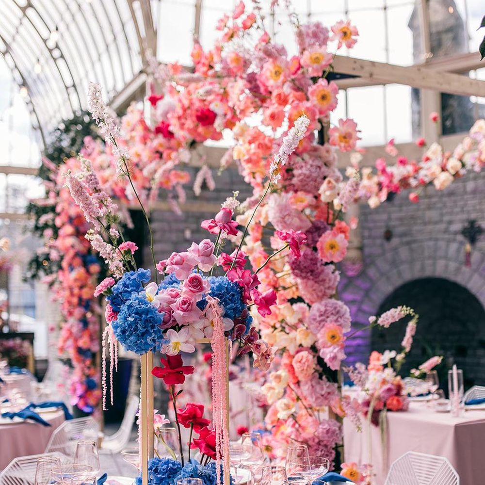 Botanical wedding with incredible wedding table centrepieces made up of blue, pink, and red wedding flowers 