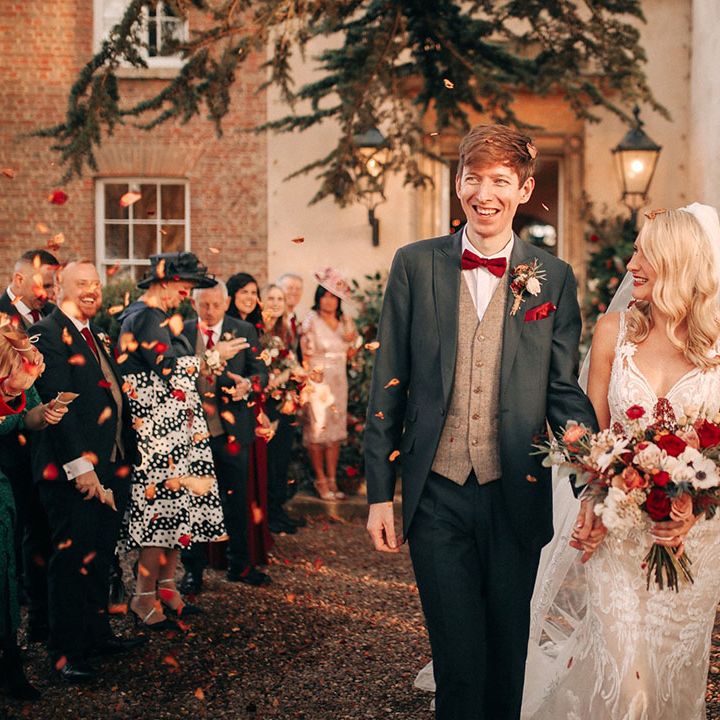 Bride holding red and white wedding bouquet with white anemones walking out with the groom for confetti exit 