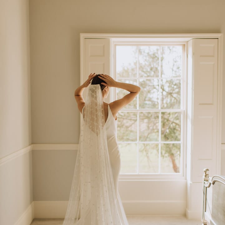Bride looking out of the window at Reymerston Hall 