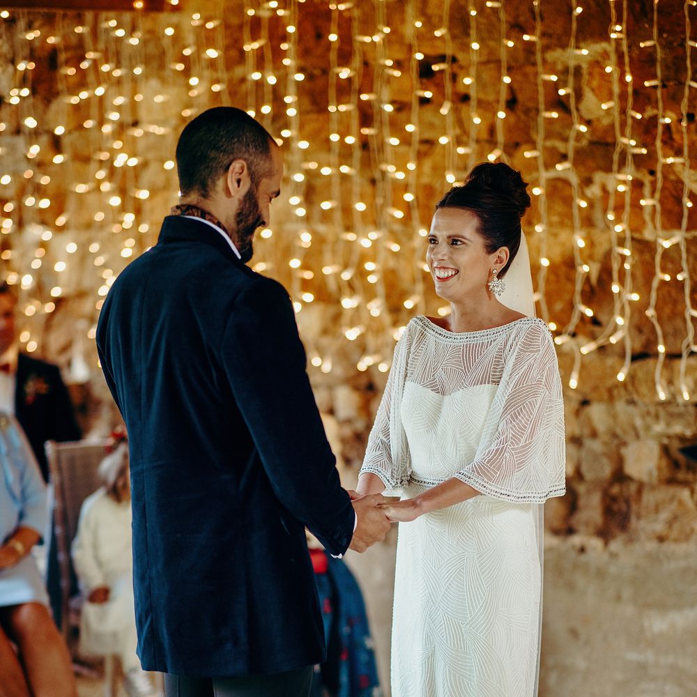 Bride & groom say their vows with fairy lights curtain in background