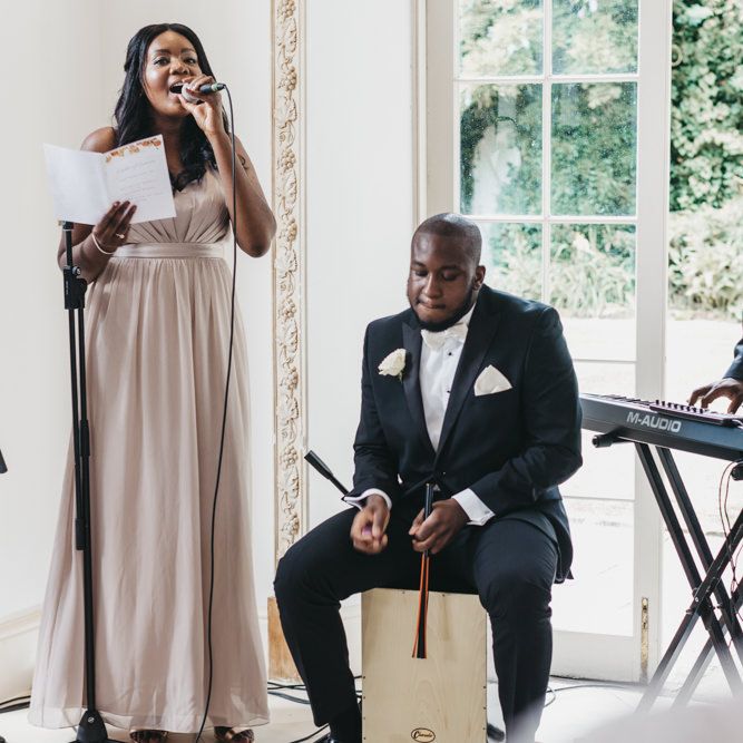 Bridesmaid in a dusky pink dress singing during the Northbrook Park wedding ceremony 