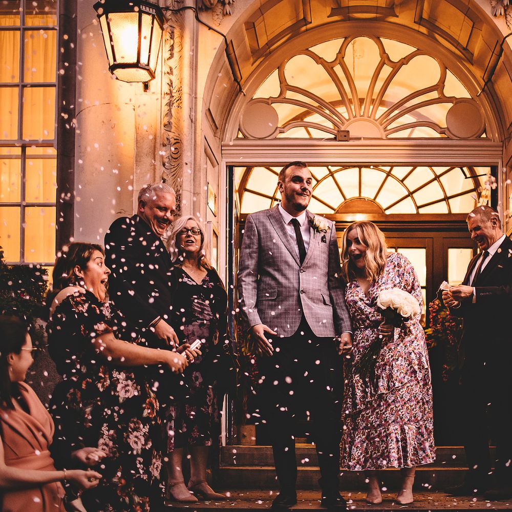 Bride & groom have confetti throw around them by wedding party after Town Hall wedding