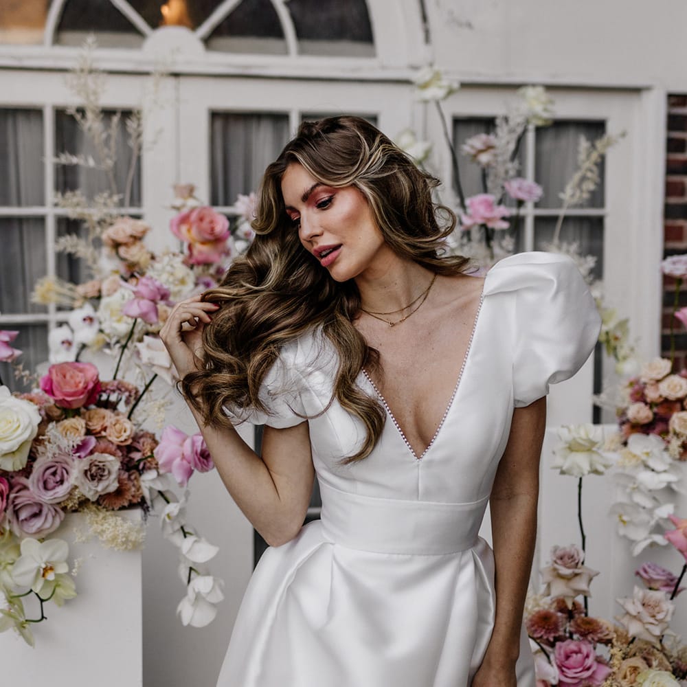 Beautiful bride with long wavy hair in a taffeta wedding dress with plunging neckline 