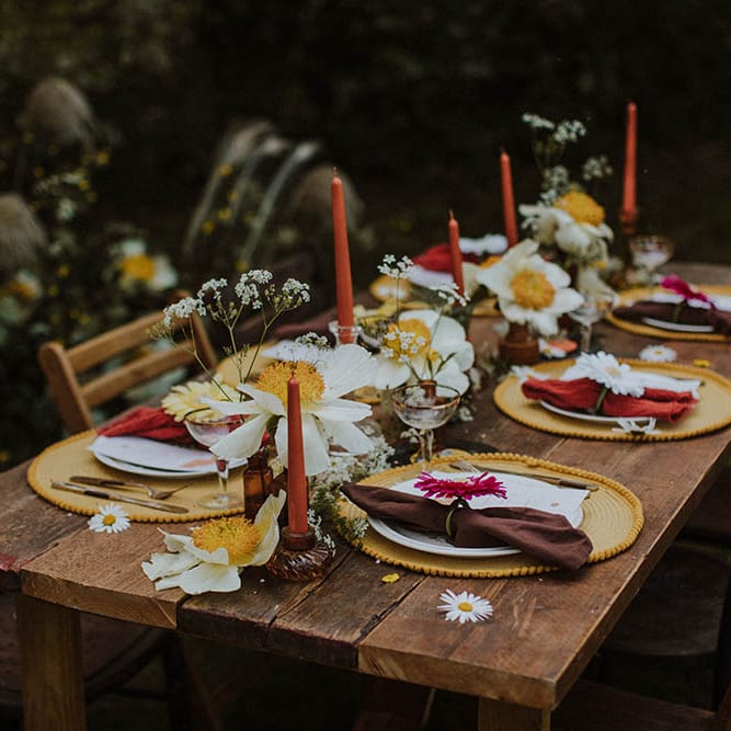 Intimate sixties wedding reception table decor with white peonies, orange candles, brown vases and yellow placemats 