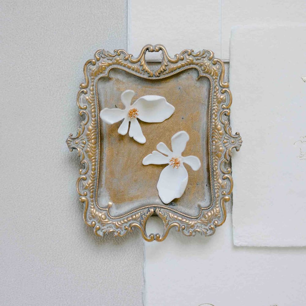 White flower petal earrings on a gold dish 