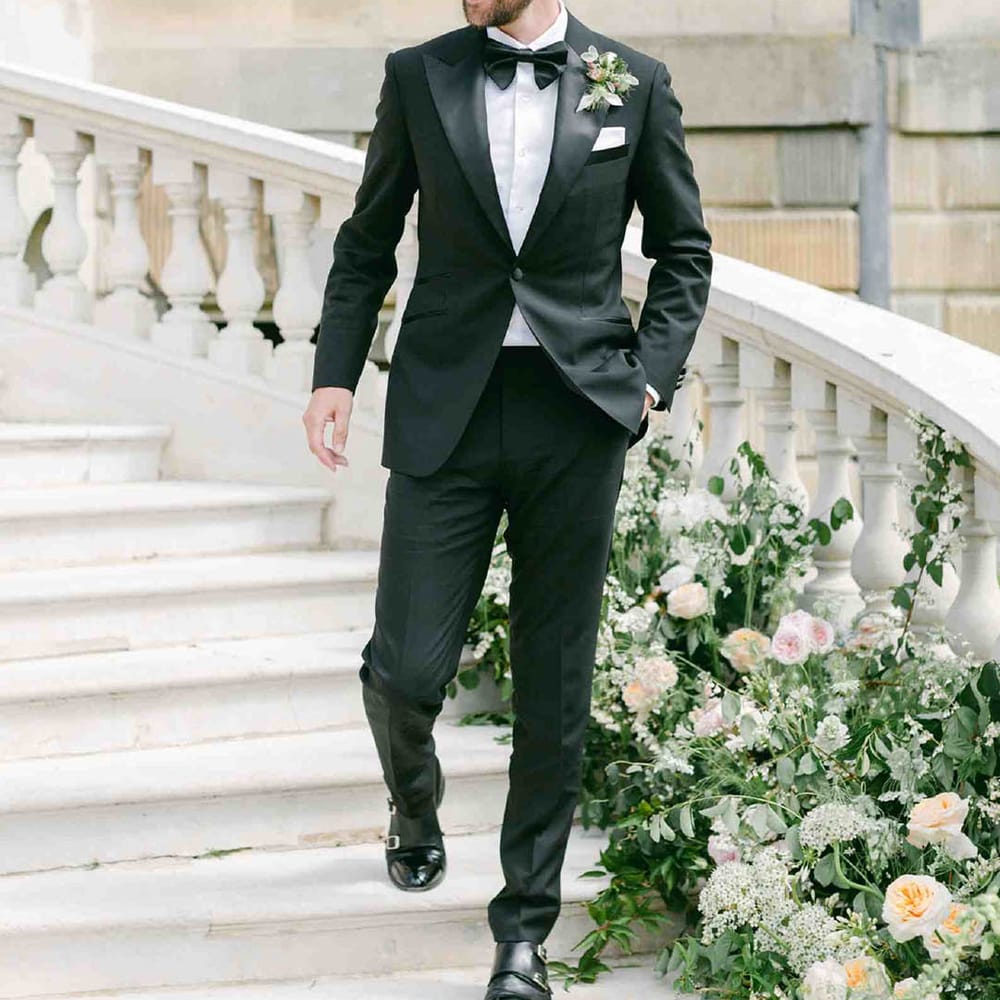 Stylish groom in a black tuxedo at country house wedding venue 