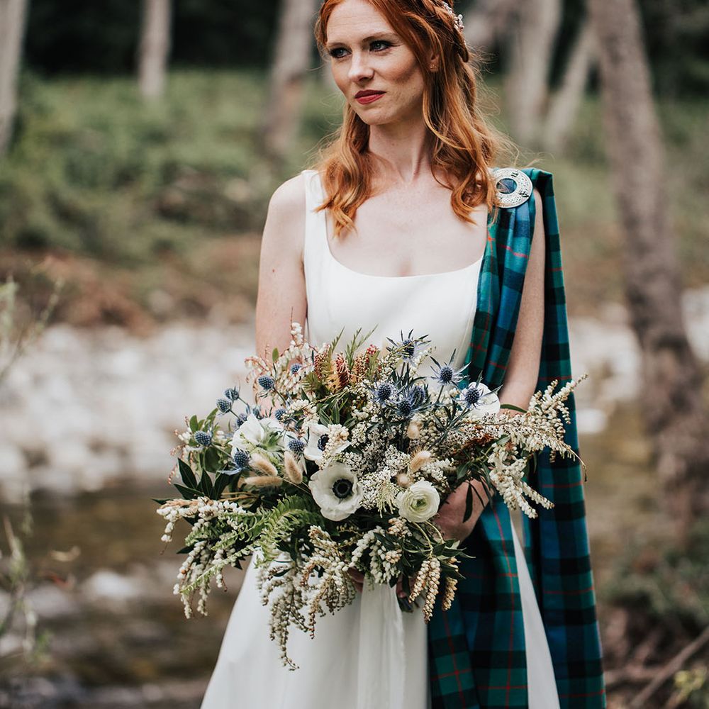 beautiful bride with red hair holding an anemone wedding bouquet with thistles and foliage 