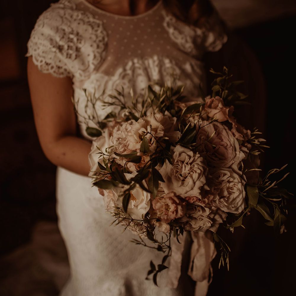 Bride in a lace wedding dress holding a romantic pink and white wedding bouquet 