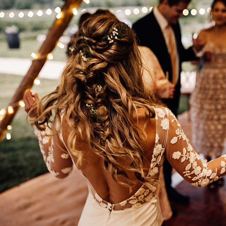 Bride with braided hairstyle and flowers braided in dances in lace wedding dress 