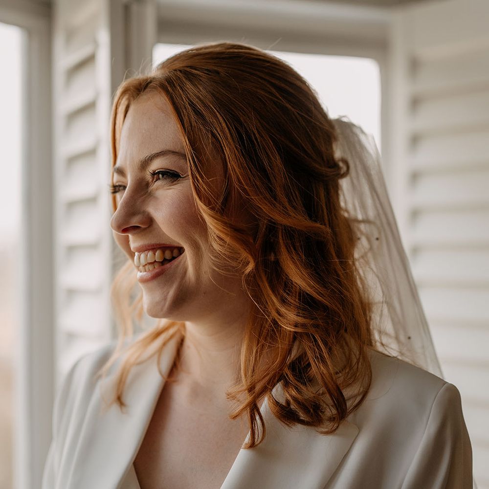 Bride wears her red hair in loose curls complete with veil to the back