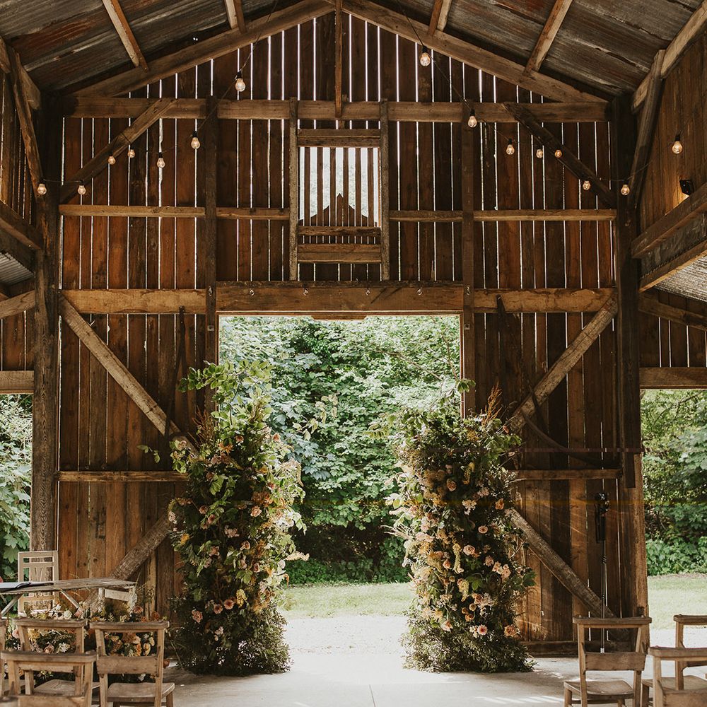 Rustic Nancarrow Farm wedding venue with two flowers columns for altar decoration and wooden chairs 