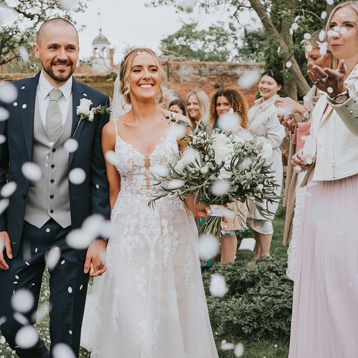 Bride and groom walk back down the aisle as confetti is thrown over the couple