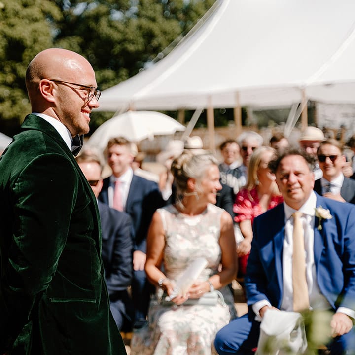 Groom wears green velvet black tie during outdoor wedding ceremony