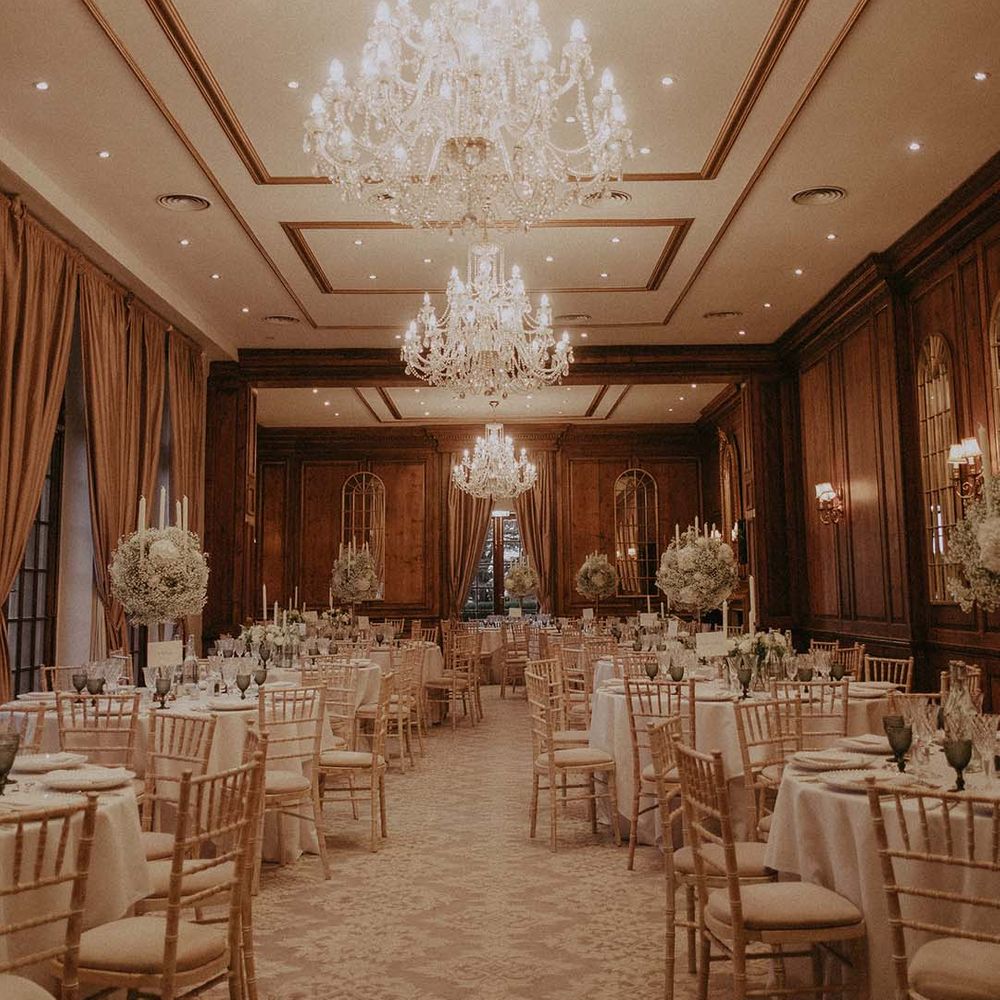 Reception room at Hedsor House with three large chandeliers, burnt orange curtains and large wreath floral decorations