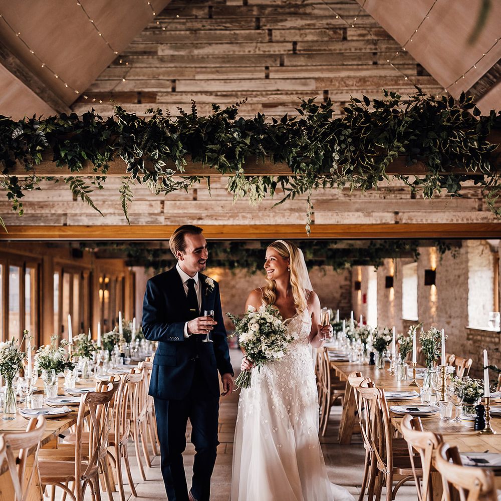 Old Gore Barn wedding venue decorated with classic greens and whites with the bride and groom standing in the aisle 