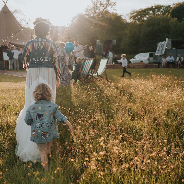 Bride walks with her son in personalised denim jackets during golden hour 