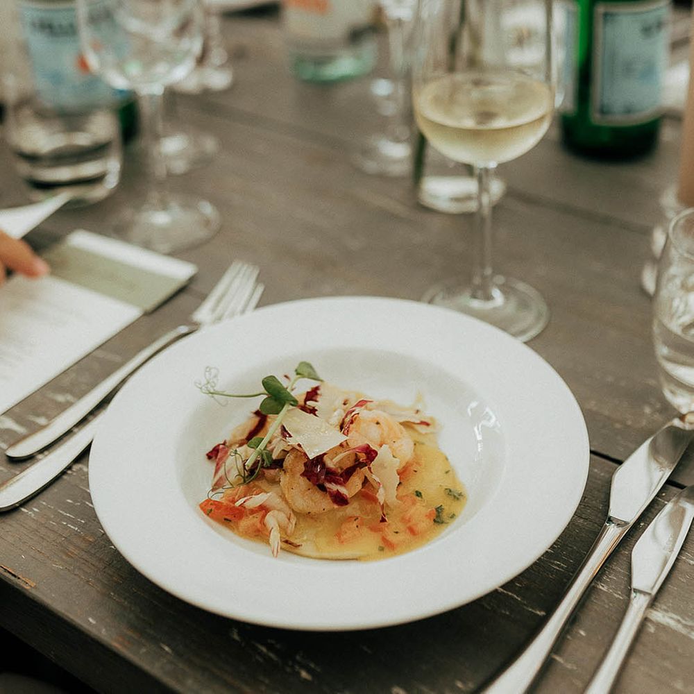 Wedding reception catering in white bowls on wooden banquet tables 