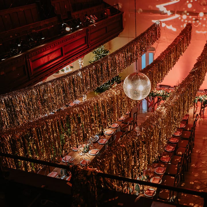 Gold wedding streamers, large hanging disco ball, Christmas tree projection and large Christmas tree in reception room of Old Marylebone Town Hall wedding venue