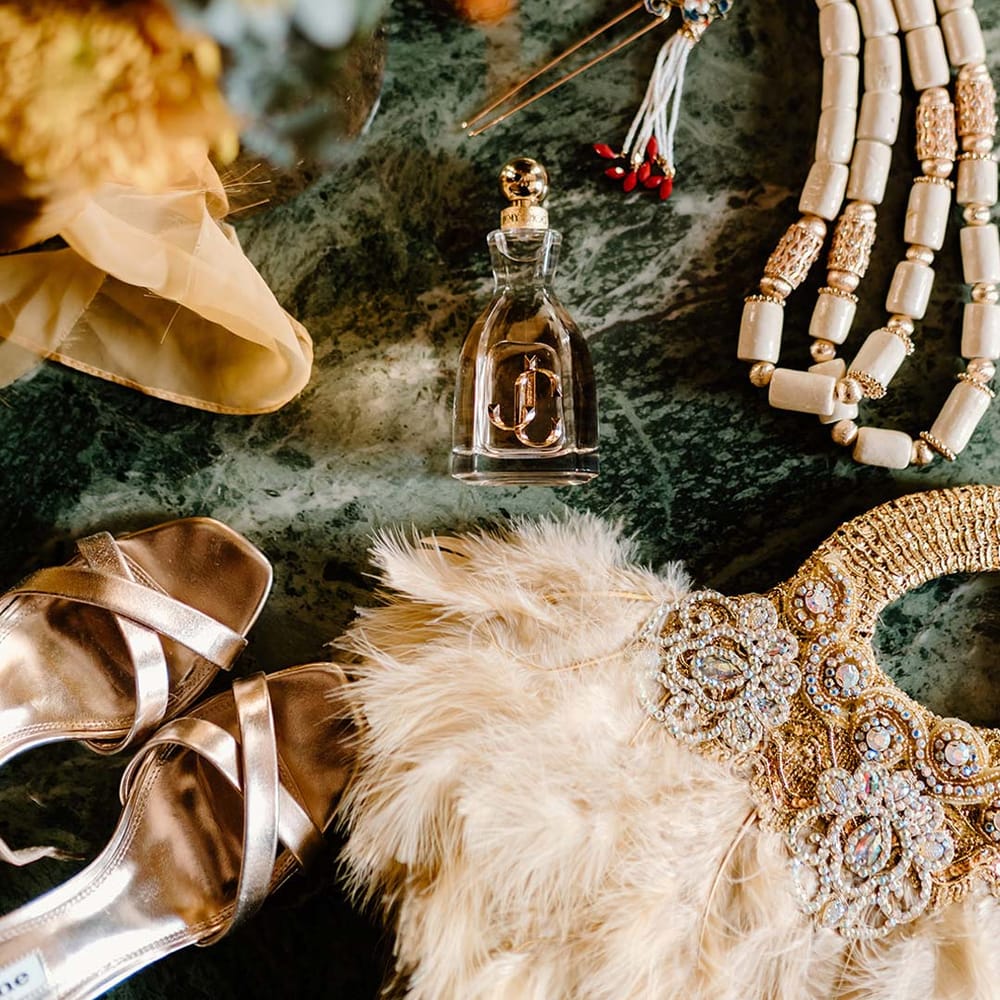 Jimmy Choo wedding perfume surrounded by alternative bridal accessories, orange flowers and strappy gold wedding heels at Broadfield Court
