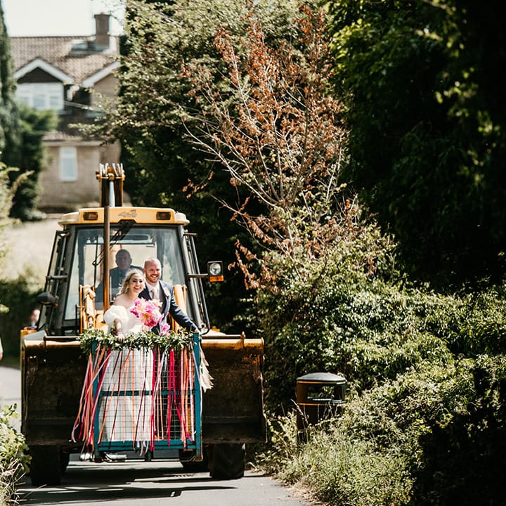The bride and groom ride in the JCB wedding transport over to the reception driven by the bride's grandad 
