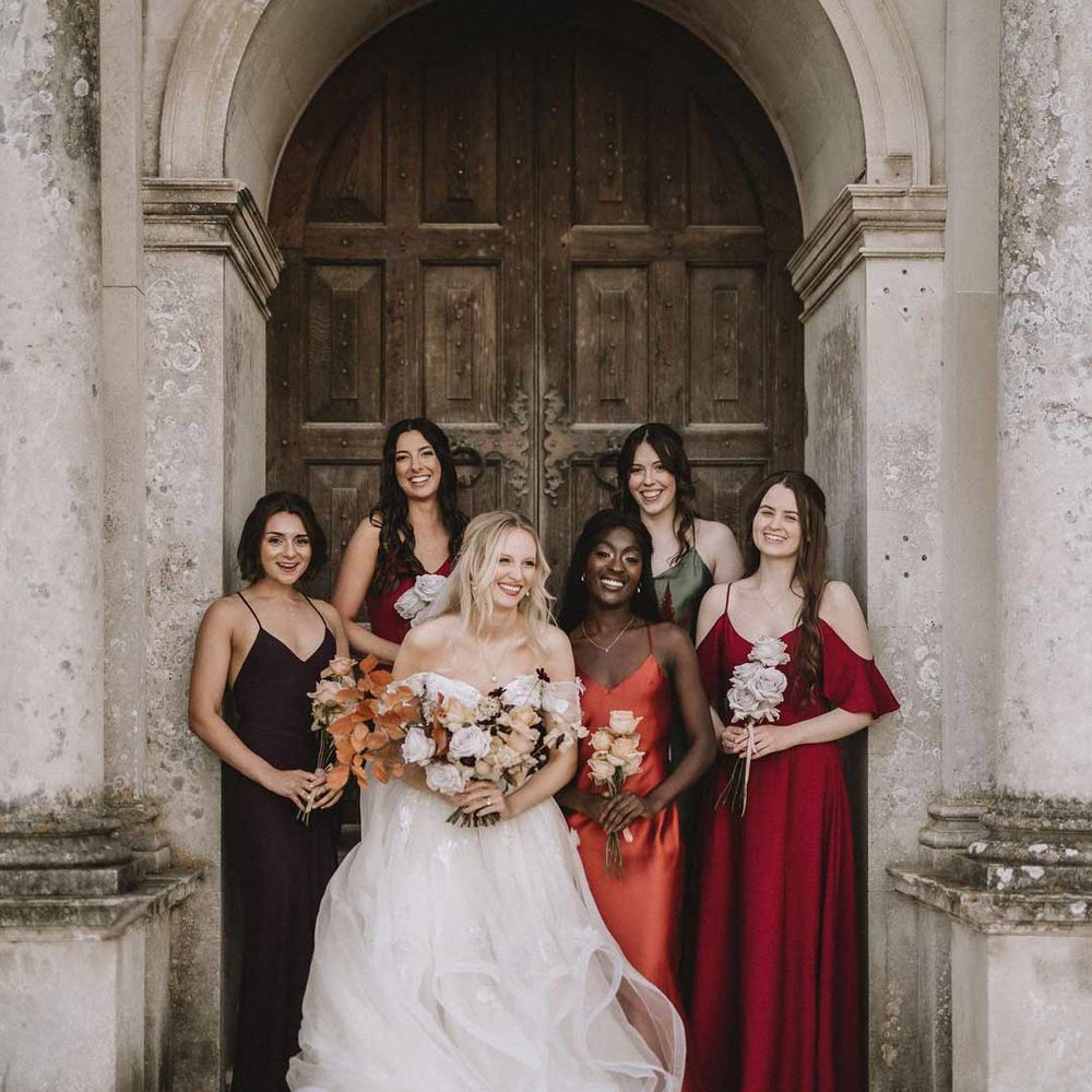 Bride in tulle off shoulder princess wedding dress with bridesmaids in mismatched satin slip bridesmaid dresses 