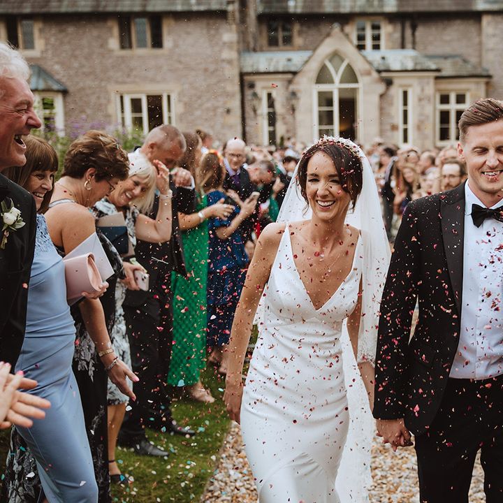 Bride in slip gown walking hand in hand with the groom in black tie 
