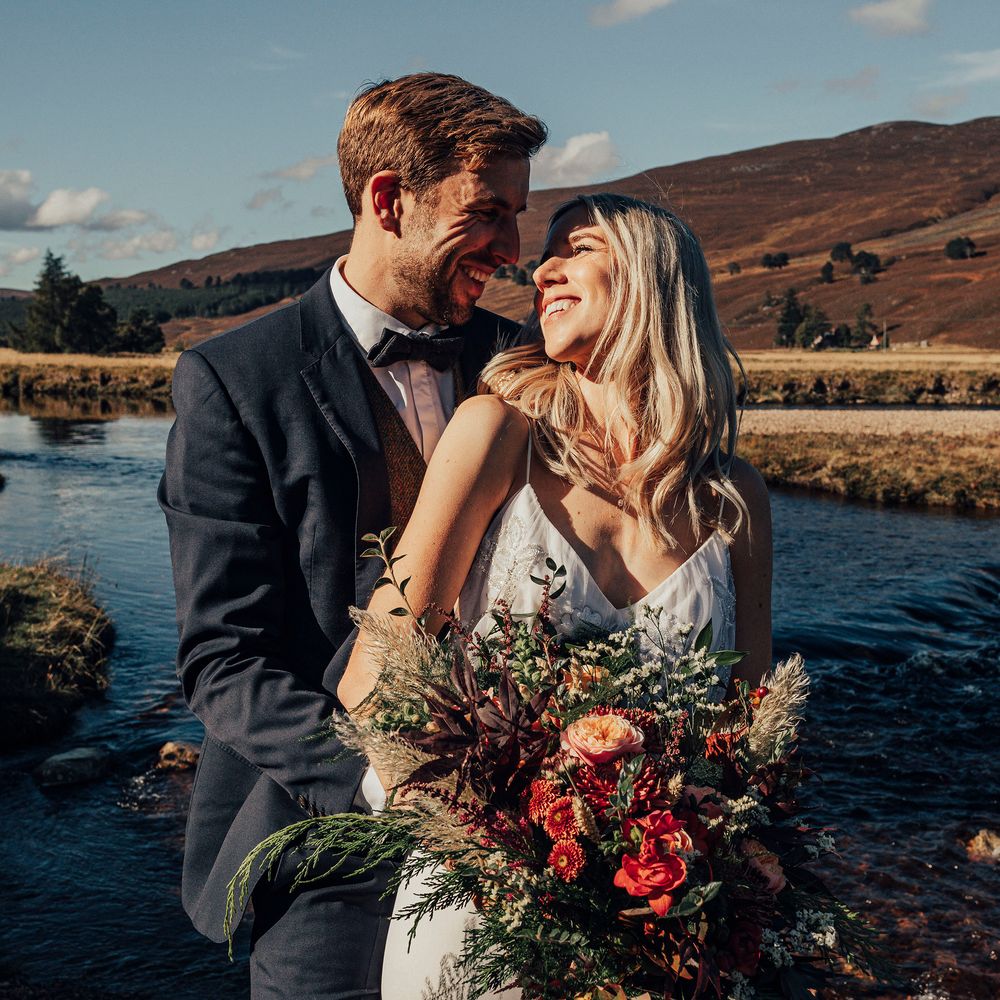 Bride & groom with lake and hills in background 