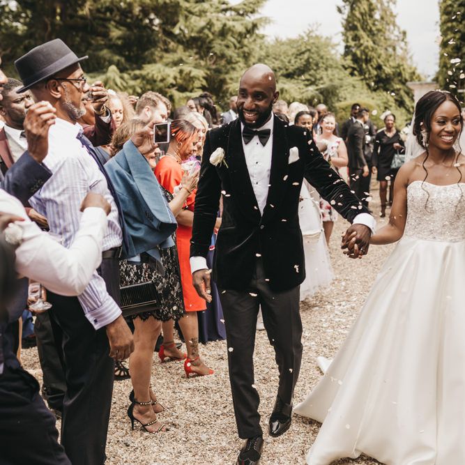 Confetti moment with Black groom in a velvet tuxedo jacket and Black bride in a strapless Oleg Cassini wedding dress with beaded bodice