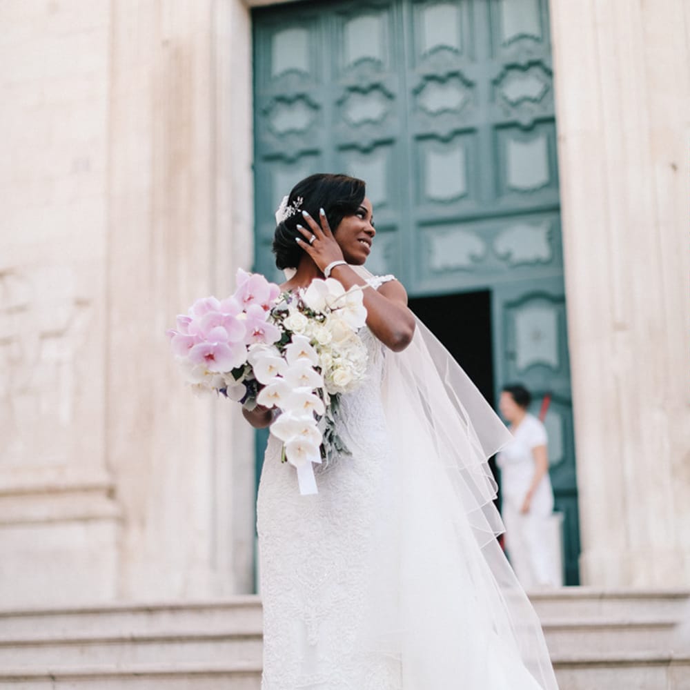 Beautiful bride wearing a lace wedding gown holding pink and white bridal bouquet 