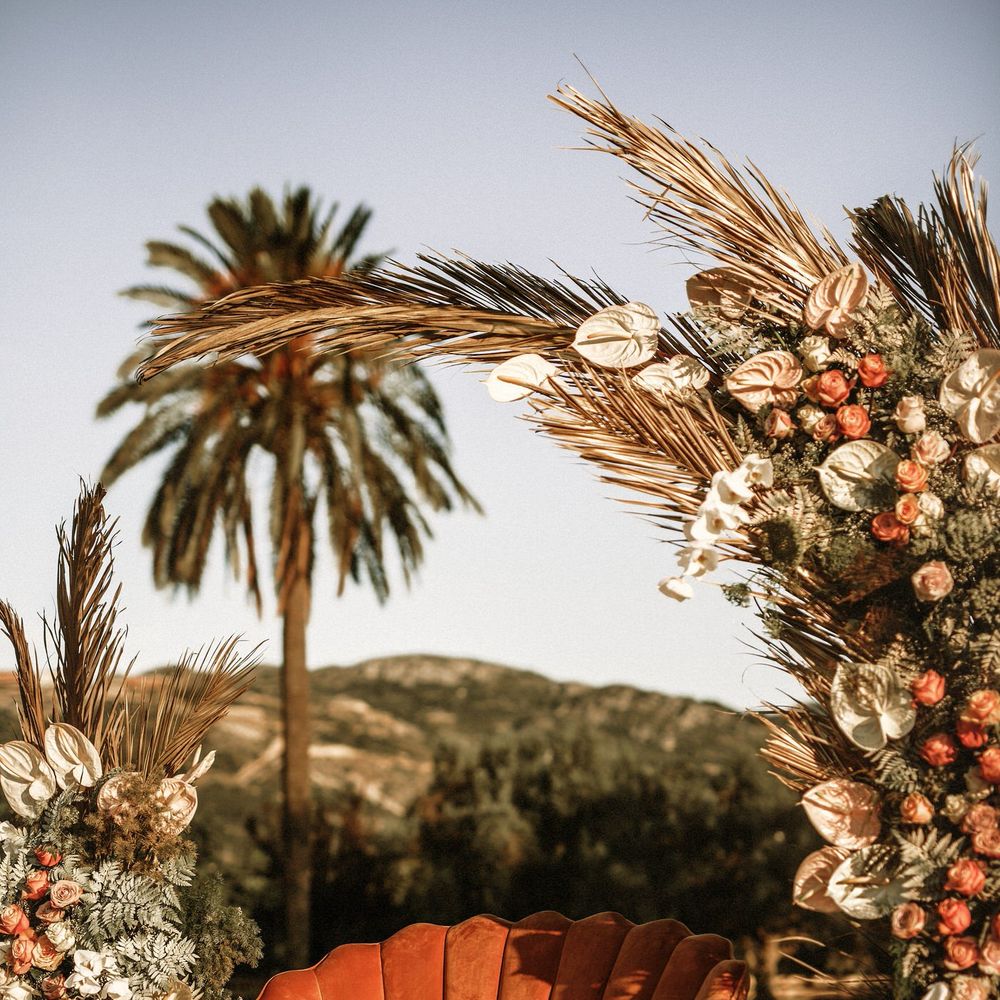 Orange velvet love seat with scalloped back at the altar with boho wedding flowers decor 