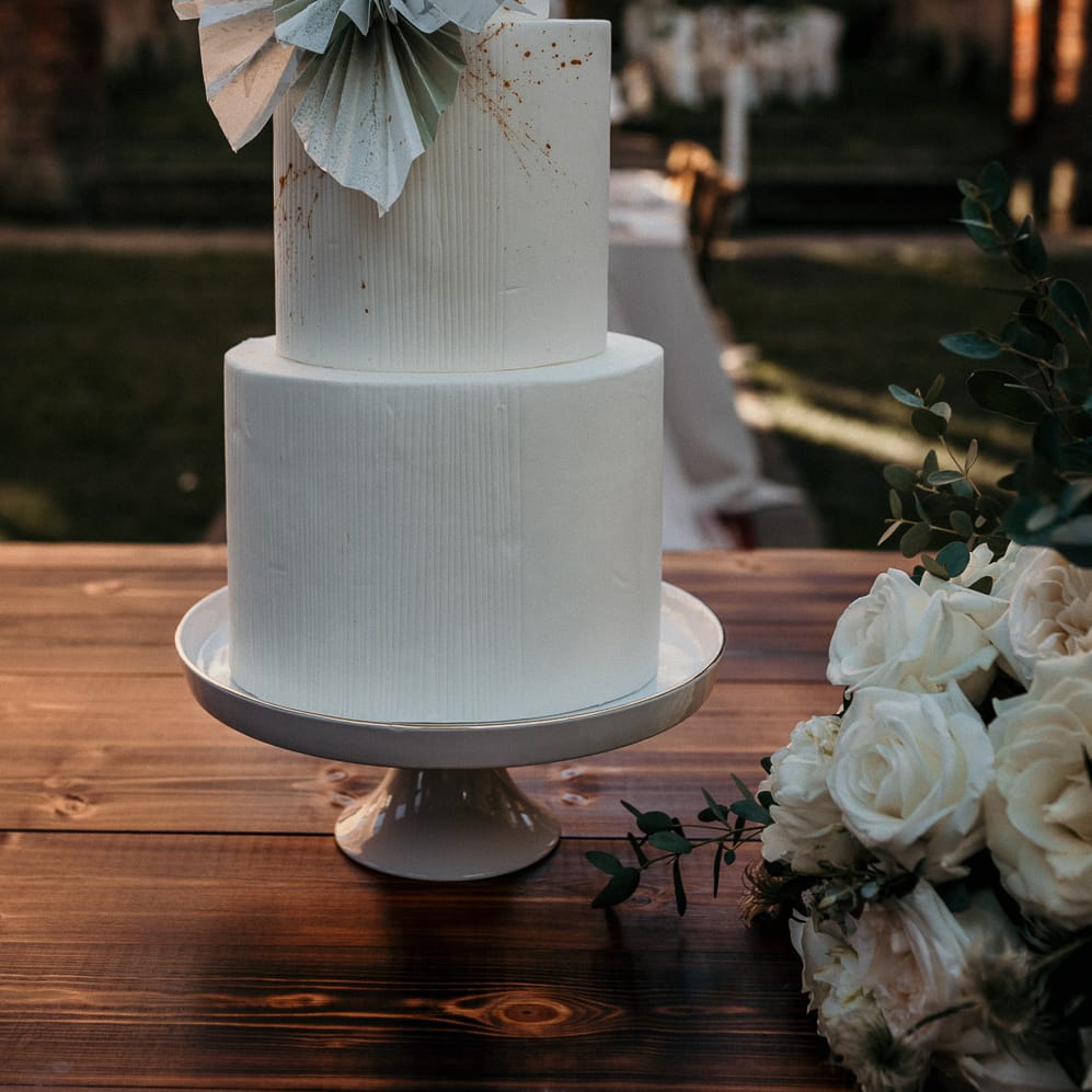 Tall three tier wedding cake on a white cake stand with fan design 
