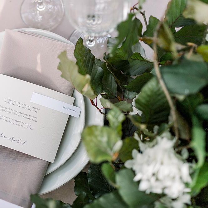 Place setting with white tableware, beige napkin and contemporary menu card