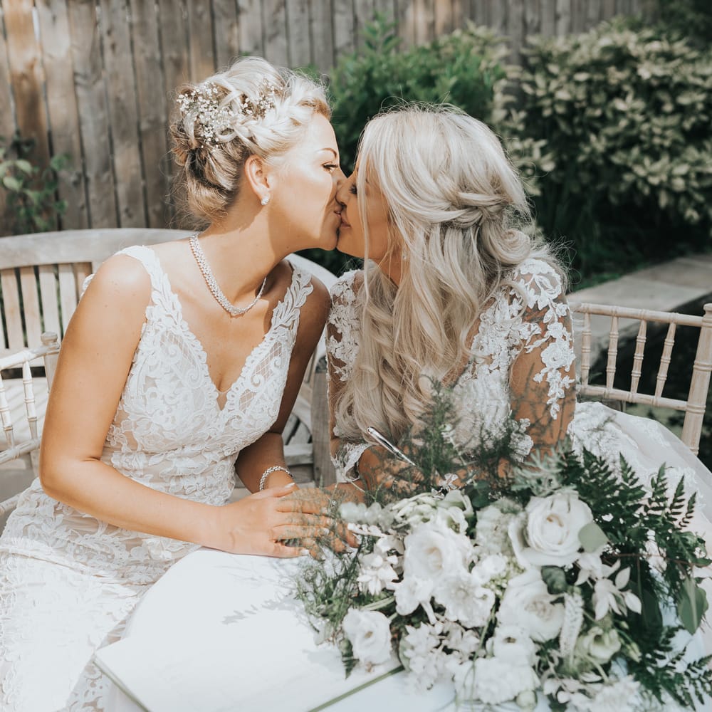 A lesbian couple kiss during a wedding portrait session. 
